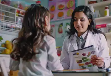 Fotografía de un médico nutriólogo con un infante, mostrando comida saludable y poniendo en práctica lo aprendido en el diplomado en nutrición pediátrica.